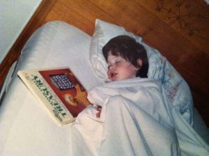 The author as a girl, sleeping with a book next to her.